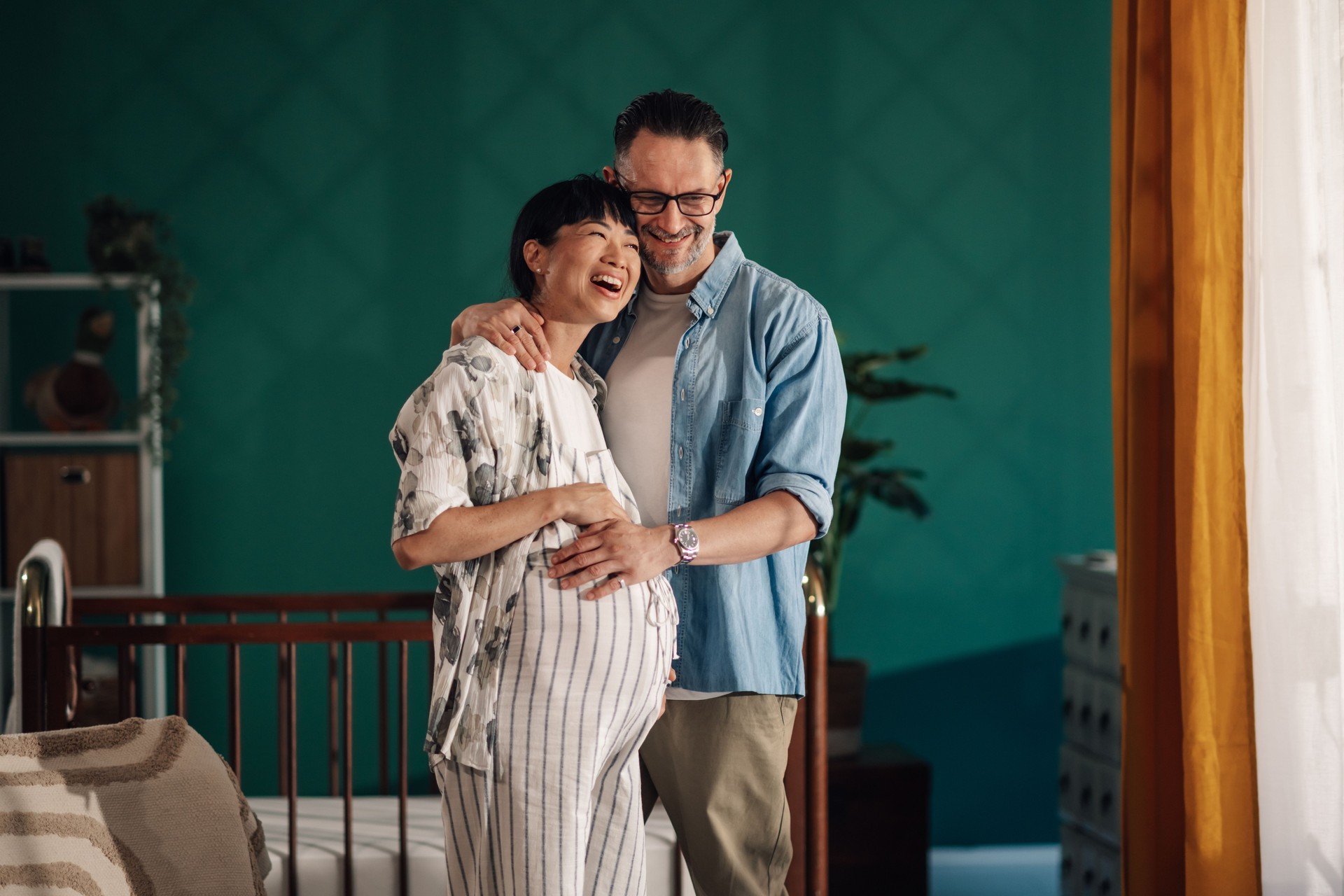 Happy couple embracing pregnant belly in nursery